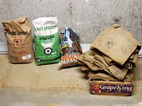 Full view of all items in the lot: two limestone bags, one bird netting bag and a pile of burlap sacks.