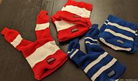 Five reversible toques made from hockey socks, two blue and three red, on dark surface.