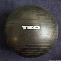Close-up photo of black TKO exercise ball with textured surface.