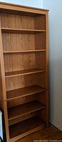Full view of the Prepac wooden bookcase showing all six shelves, oak finish with wood grain, and overall condition.