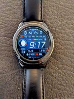 Samsung Gear S2 Classic smartwatch showing digital watch face with date, moon phase, step count, notifications, and battery percentage.