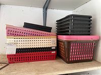Stacked plastic baskets and trays in various colors and sizes on a shelf