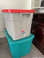 Grey Sterilite storage bin with red lid stacked on teal storage bin with matching teal lid, showing size and color details.