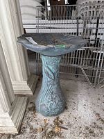 Front view of decorative plastic bird bath showing leaf design basin and floral detailed base.