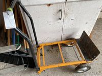 Photo of the yellow metal frame cart with black rusted plate and three wheels, showing the side and handle area