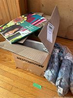 Box partially open showing yarn bags next to it on a wood floor.