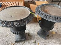 Pair of tall black resin planters with removable glass tops, placed outdoors on a gravel surface.