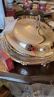 Close-up of the silver plated covered serving dish showing the lid with ornate handle and reflective surface.