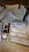 Photo of three silver plate coasters, one cake cutter, and serving spoons on carpet.