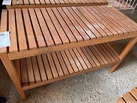 Wooden slatted rectangular table with a lower matching shelf, showing some white marks on the top surface.
