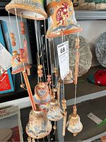 Close-up view of three terra cotta wind chimes showing detailed painted designs and bead decorations