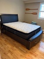 Overall view of black faux leather upholstered queen bed frame with optional mattress
