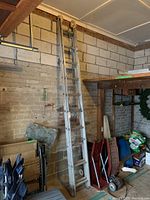 Full view of the 10 ft aluminum extension ladder leaning against a brick wall with adjacent stored items.
