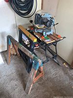 Delta 10-inch compound miter saw mounted on Black & Decker Workmate 400 with two work horses beneath