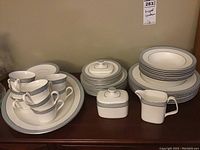 Full view of the arrangement of dinnerware including stacked plates, bowls, tea cups, saucers, sugar bowl, creamer, and platters.