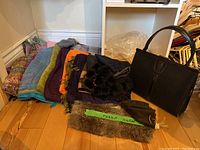 Photo showing multi-colored scarves and shawls laid out, rabbit fur collar, and black handbag next to them.