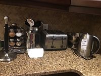 Overview of items on countertop including paper towel holder, spice rack, kitchen utensil holder, toaster, mixing bowl, and electric kettle