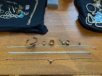 Photo showing multiple silver rings, necklaces, and single earrings laid out on a wooden surface for clear item view.