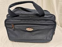 Front view of dark blue Air Canada travel bag with visible front zippered pocket and logo plaque.