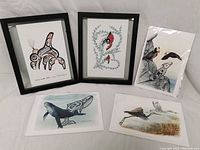 Five First Nations prints, two framed and three unframed, arranged on white cloth backdrop.