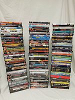 Three stacks of varied DVDs against a white backdrop showing many movie titles.