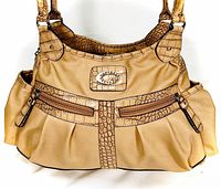 Front view shows brown faux leather with textured alligator-style accents, two zippered pockets on front, and Guess logo plaque.