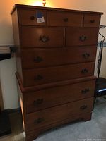 Tall wooden dresser with multiple drawers, shown with wooden and metal handles, photographed from front, showing overall condition and size