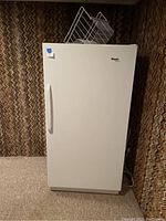 Front view of closed white upright freezer showing exterior and brand logo