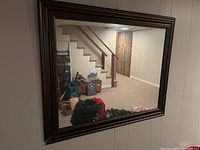 Full view of mirror reflecting basement stairs and other items in room.