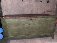 Side view of the wooden hope chest showing green painted exterior with scratches and wear.