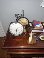 Wooden table with two clocks, small decorative items, books and photo albums.
