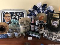 Overview photo showing the entire Penn State themed collector's lot on display including tray, glasses, coke bottles, ceramic figurines, book, wreath, bear plush, bus model, and purse.