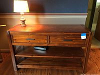 Front view of wood sofa table with two drawers and lamp on top
