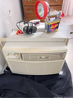 White-Westinghouse window air conditioner with vintage flashlight placed on top.