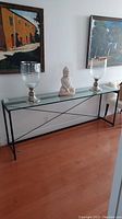 Front view of long glass top console table with decorative items on top