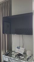 Front view of wall-mounted Insignia 55" Fire TV with cables and remote on chest below