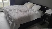 Full view of black wooden platform bed frame with mattress and bedding from side