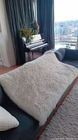 Off-white lambskin rug laid over a gray sectional sofa showing full length