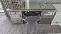 Full view of mirrored desk with clear chair and desk lamp