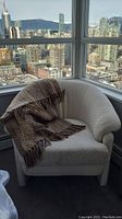 Arm chair in corner near window with Urban Barn throw placed over one side