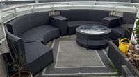Full overview of black resin wicker modular patio seating arranged in a semi-circle with coffee table and side tables