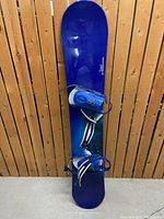 Full view of blue Rossignol Hazy snowboard with blue bindings attached, showcasing top design and bindings.