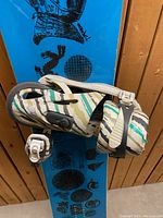 Snowboard leaning against wooden wall showing attached binding on top side