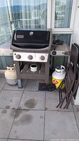 Full lot: grill, two propane tanks, two folded chairs on balcony