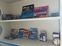 Shelf displaying various Hot Wheels and Matchbox cars in sealed packaging, including a Texaco Ford Runabout and Dodge pickup truck model.