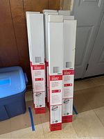 Nine boxed Project Source cordless vinyl mini blinds standing upright, packaged in branded white and red boxes.