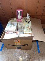Box filled with multiple Precious Moments figurines and boxed bells displayed from top view.