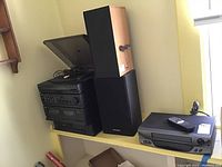 Panasonic stereo system components stacked with speakers and Broksonic VHS player on side shelf
