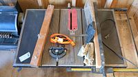 Top view of Craftsman table saw with accessories on table surface including orange strap, miter gauge, wooden guide, and cloth.