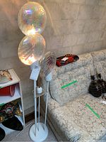 Full view of white metal floor lamp next to sofa and decorative vases